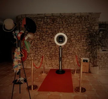 Cenário do Photobooth PlayDay: aro de luz, passadeira vermelha, cordões dourados e um cabide de props.