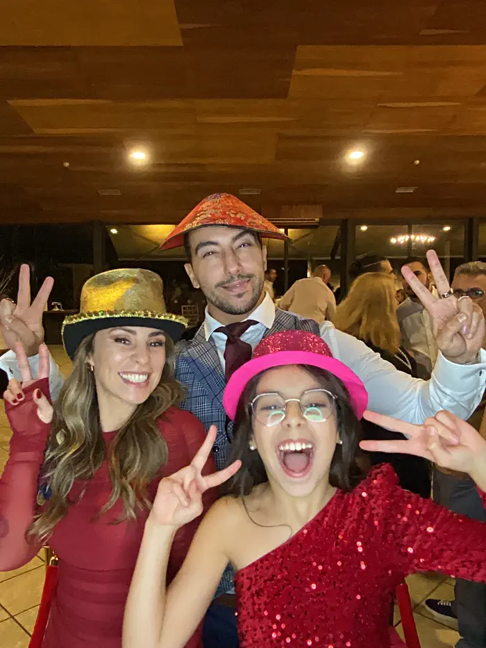 Quatro convidados a rir para o Photobooth, com chapéus de festa, óculos e colares de flores.